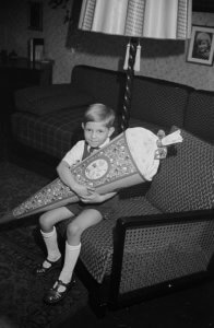 Black and white photograph of a young German boy holding a schultute or school cone, a traditional gift for grade-school aged students on their first day
