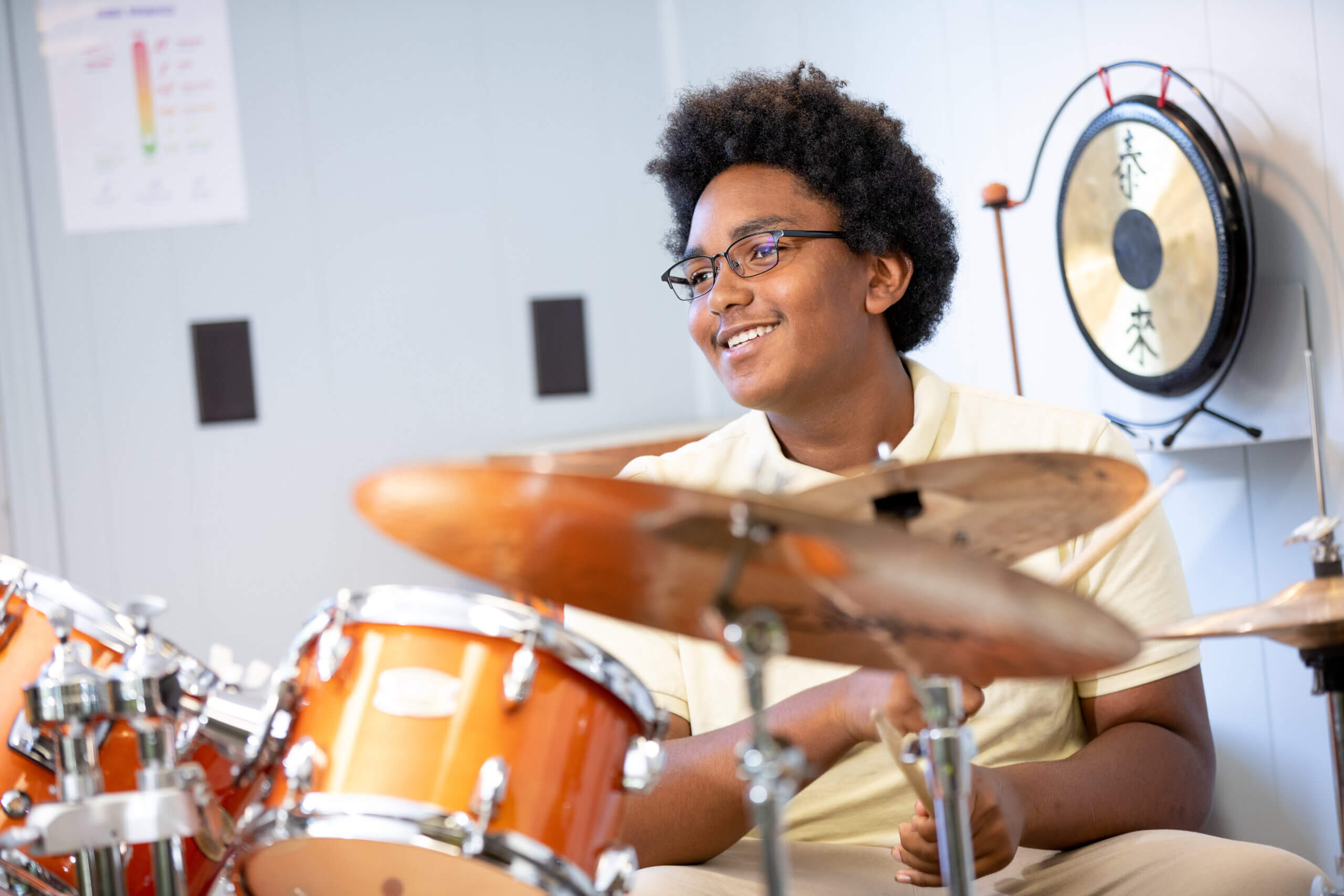 Decorative image of a student at Four Corners Montessori Academy posing for a picture at a drumset