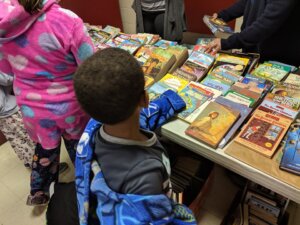 Four Corners Montessori Academy student grabbing a book at their Reading Day event.