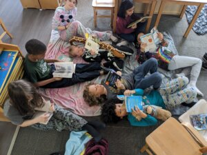 Four Corners Montessori Academy students laying down and reading during the Pajama Reading Day in the classroom.
